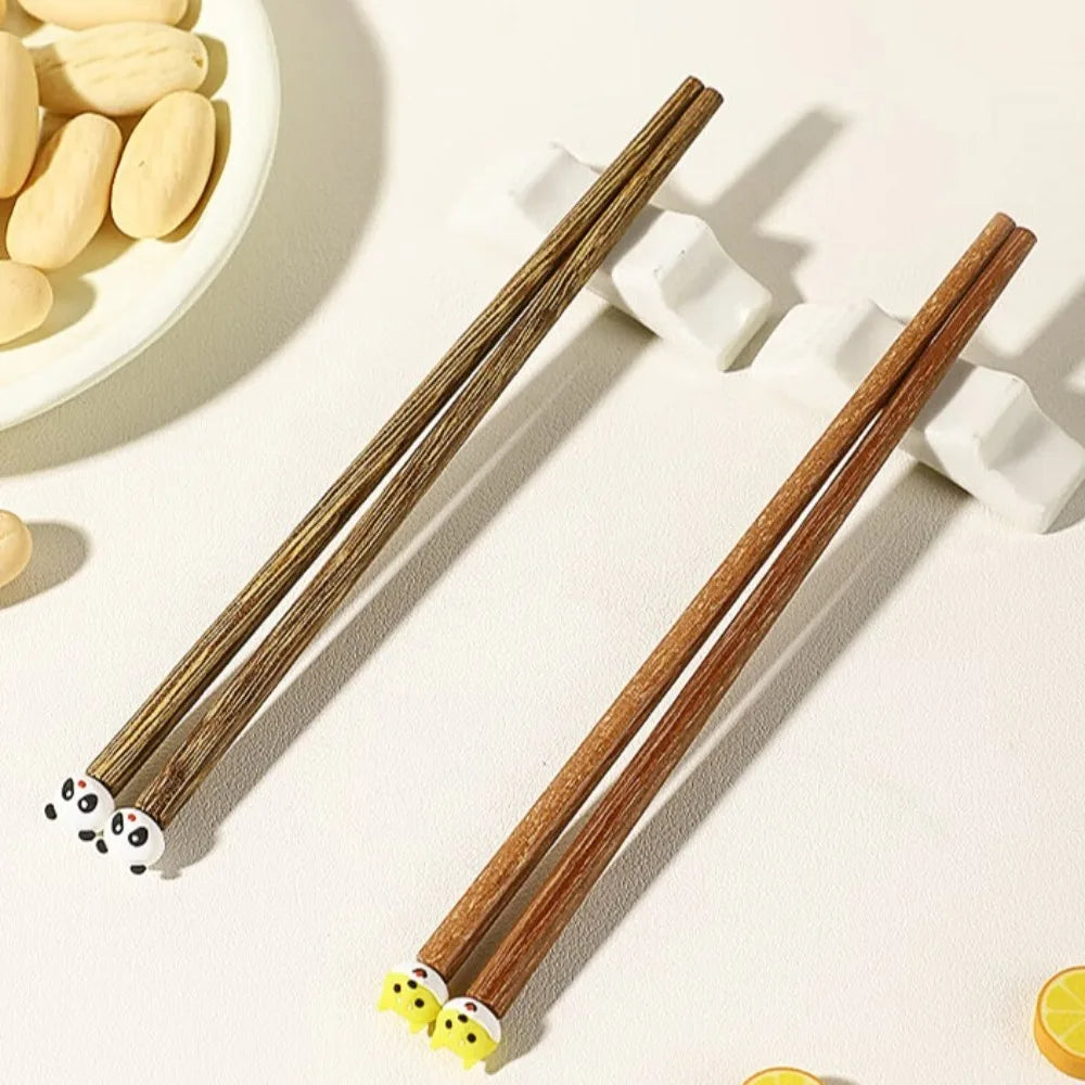 Wooden kawaii chopsticks with panda and fish designs on a light background