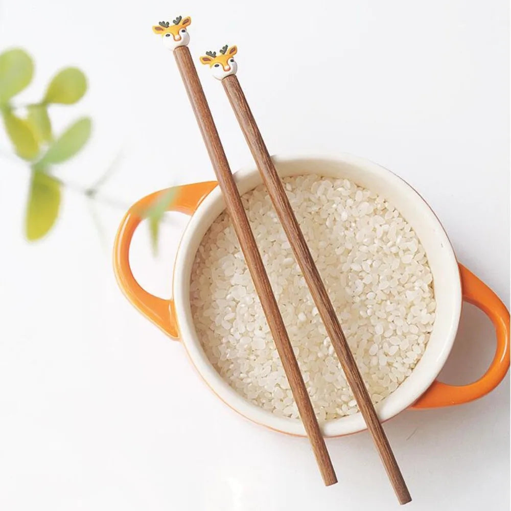 Wooden kawaii chopsticks with decorative ends on a bowl of rice.