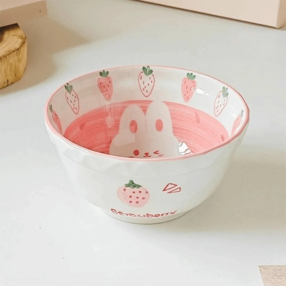 Ceramic kawaii ramen bowl with cartoon character and strawberry design on a white surface