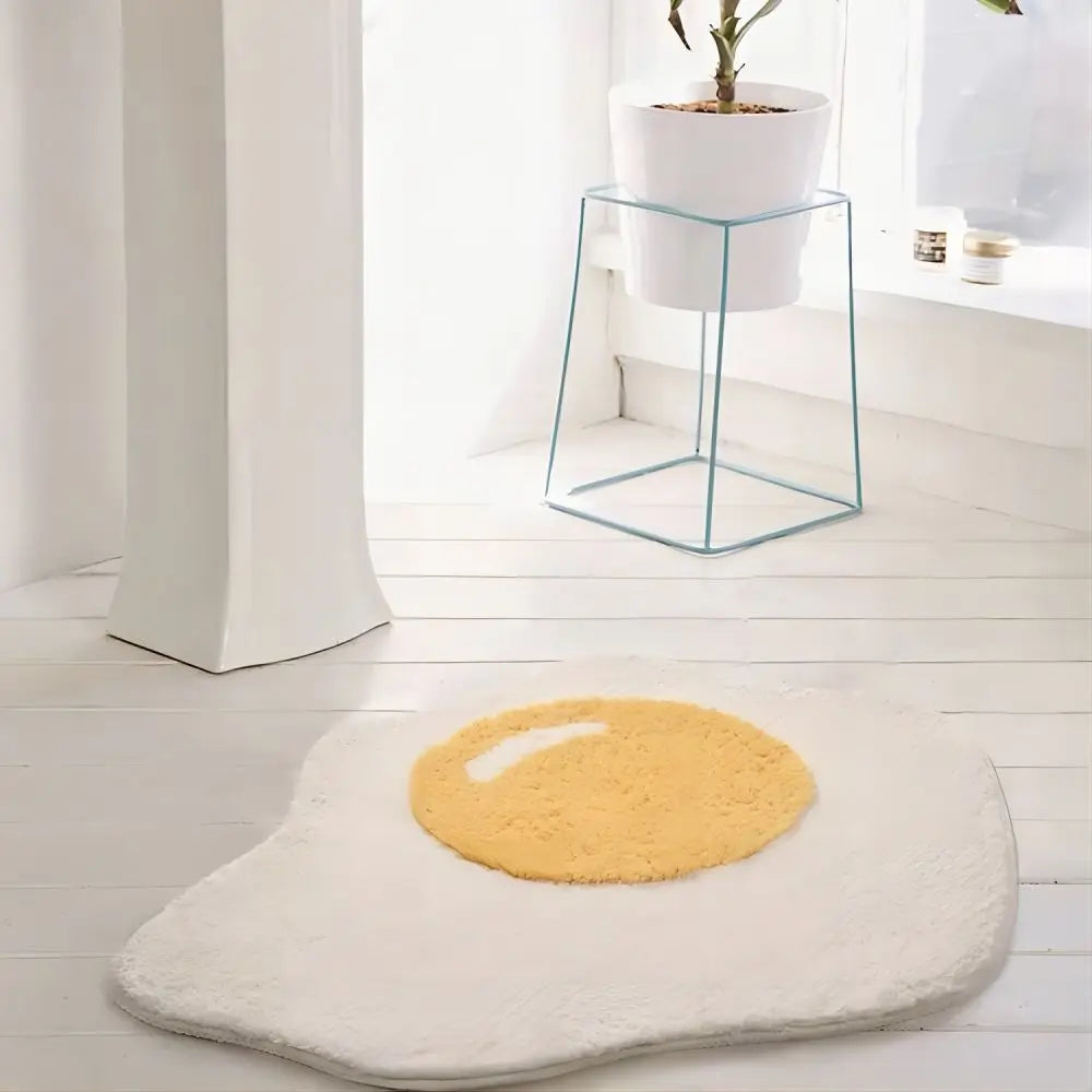 Yellow and white kawaii bath mat shaped like a fried egg on a light wooden floor.