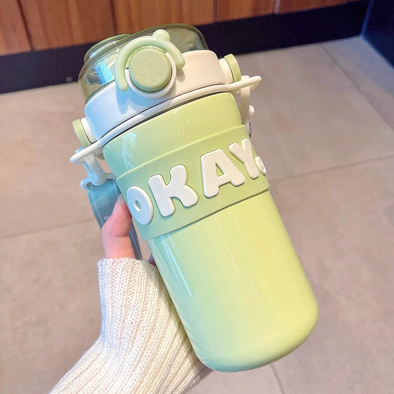 Gradient green and blue kawaii water bottle with 'OKAY' text held by a person.