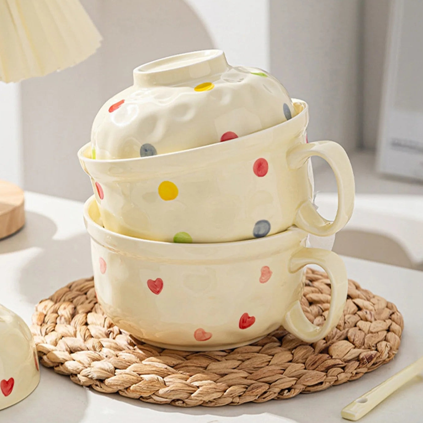 Set of ceramic kawaii ramen bowls with colorful polka dots and heart shapes on a woven mat.