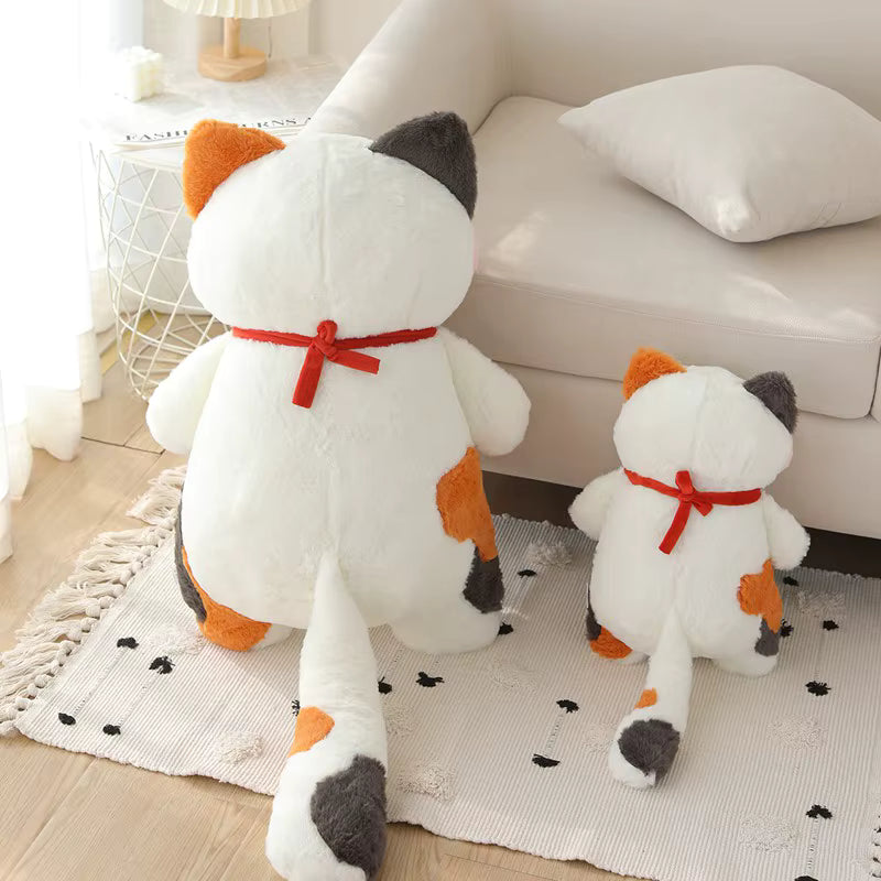 Two white plush toys with orange and gray accents on a rug in a living room.