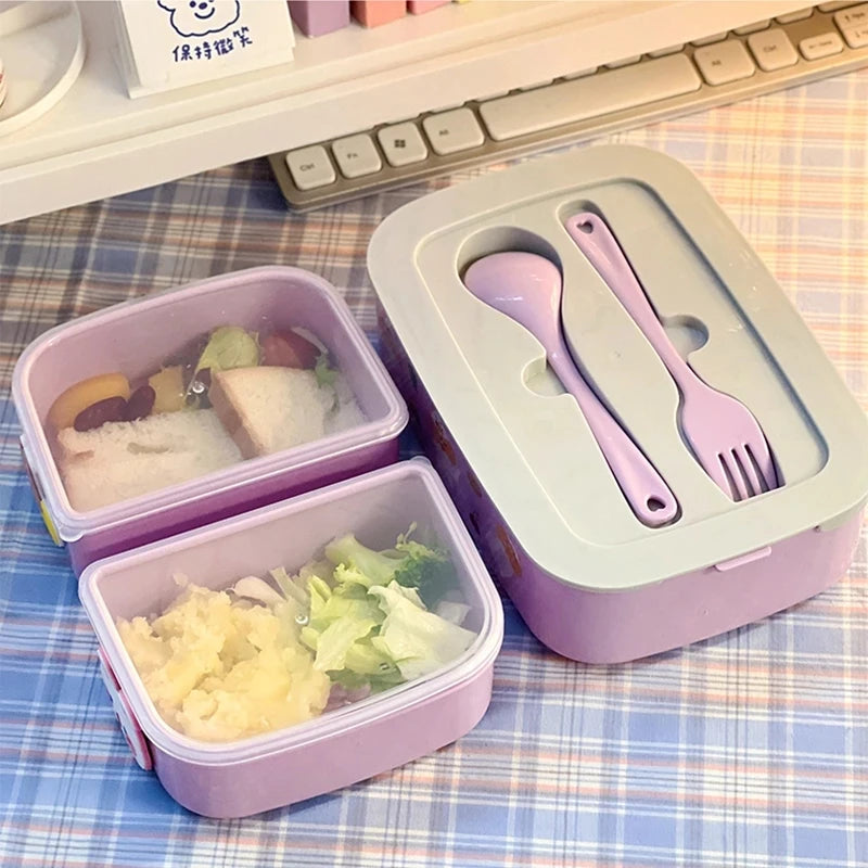 Purple kawaii bento box with compartments and utensils on a checkered tablecloth.
