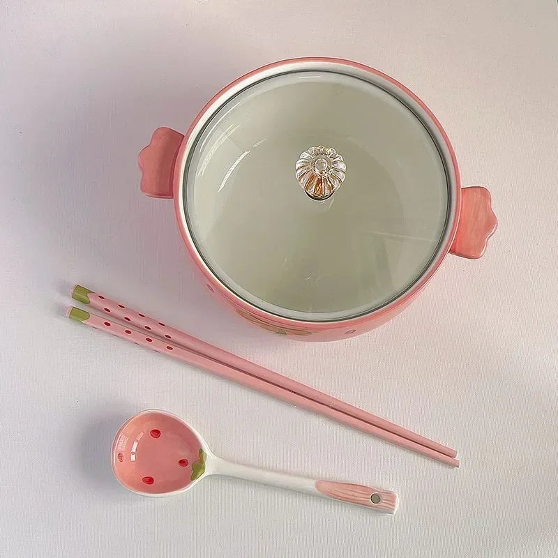 Pink ceramic kawaii bowls with lid, chopsticks, and spoon on a light gray background