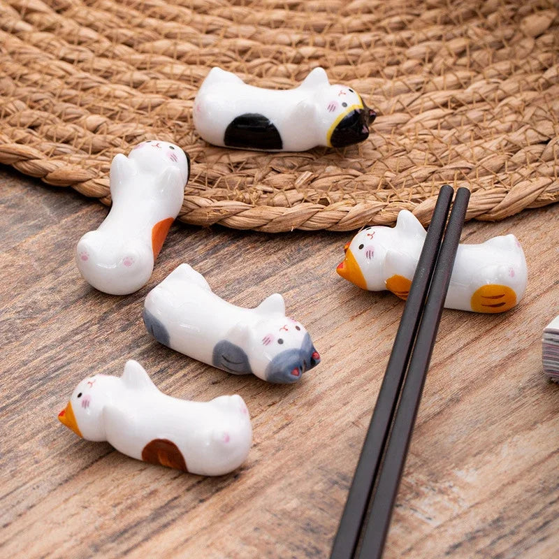 Set of ceramic animal kawaii chopstick holders on a wooden surface with chopsticks.