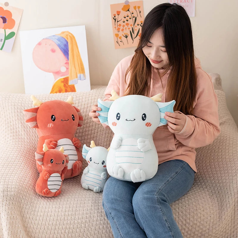 Woman holding a white kawaii plush toy with a cat-like design, surrounded by other plush toys on a couch.