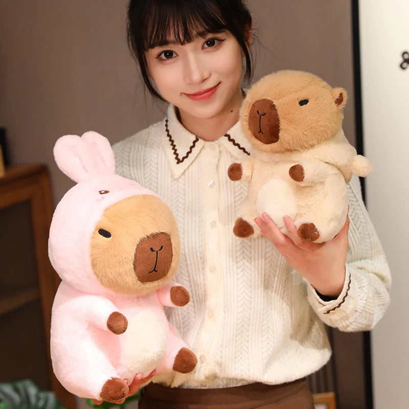 Person holding two kawaii plush toys, one pink and one brown, against a neutral background.