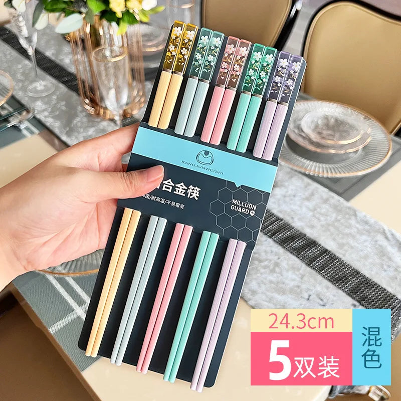 Packaged kawaii chopsticks with colorful handles held by a hand on a dining table.
