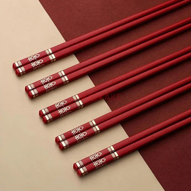 Set of red kawaii chopsticks with gold accents on a beige and brown background