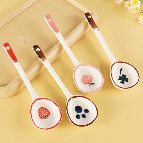 Set of four ceramic kawaii spoons with decorative ends on a yellow background