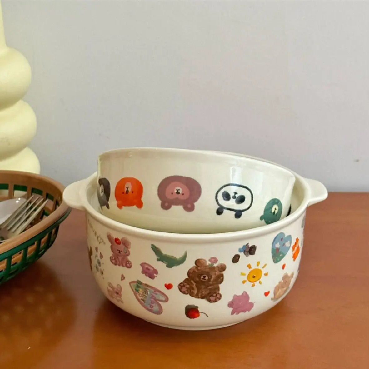 Two ceramic kawaii bowls with animal illustrations on a wooden surface.