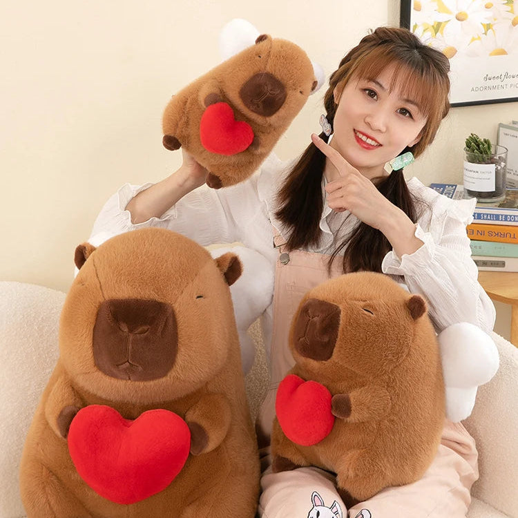 Woman holding three brown kawaii plush toys with red hearts on a light-colored couch.