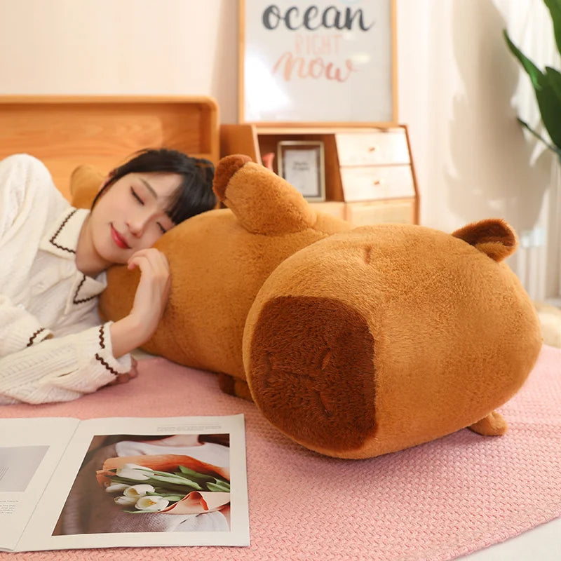 Person lying on a large brown teddy bear-shaped kawaii pillow in a cozy room.