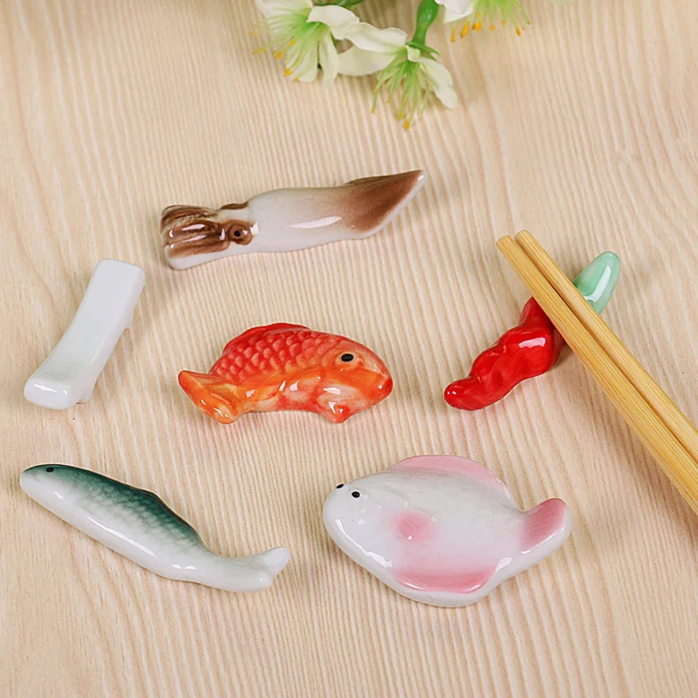 Set of ceramic fish-shaped kawaii chopstick holders on a wooden surface with chopsticks.