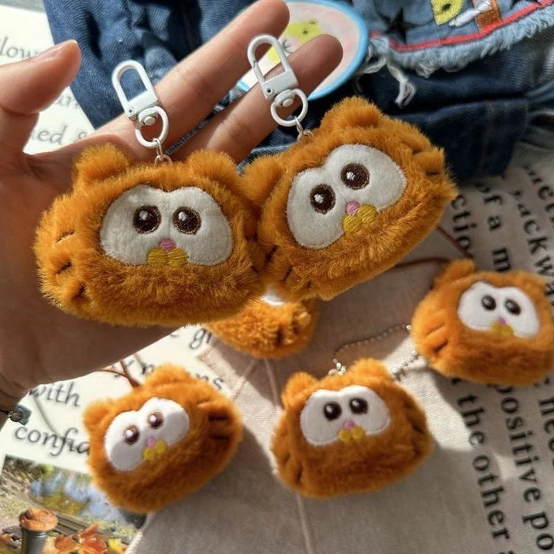 Plush kawaii owl keychains held by a hand on a newspaper background