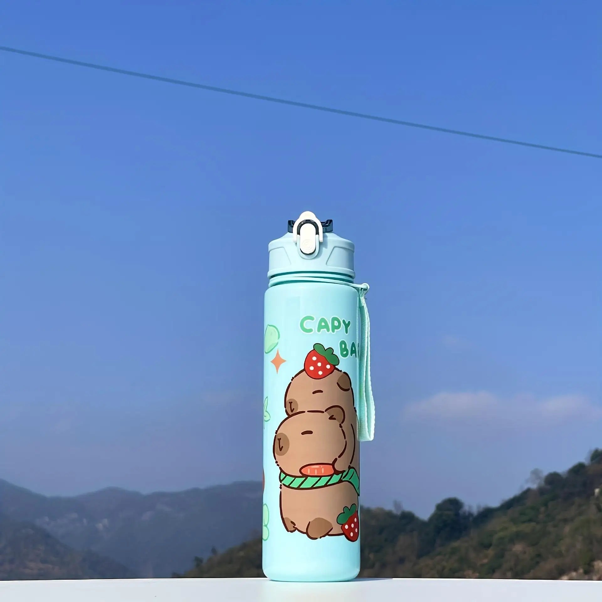 Light blue kawaii water bottle with cartoon hippo design against a mountainous background