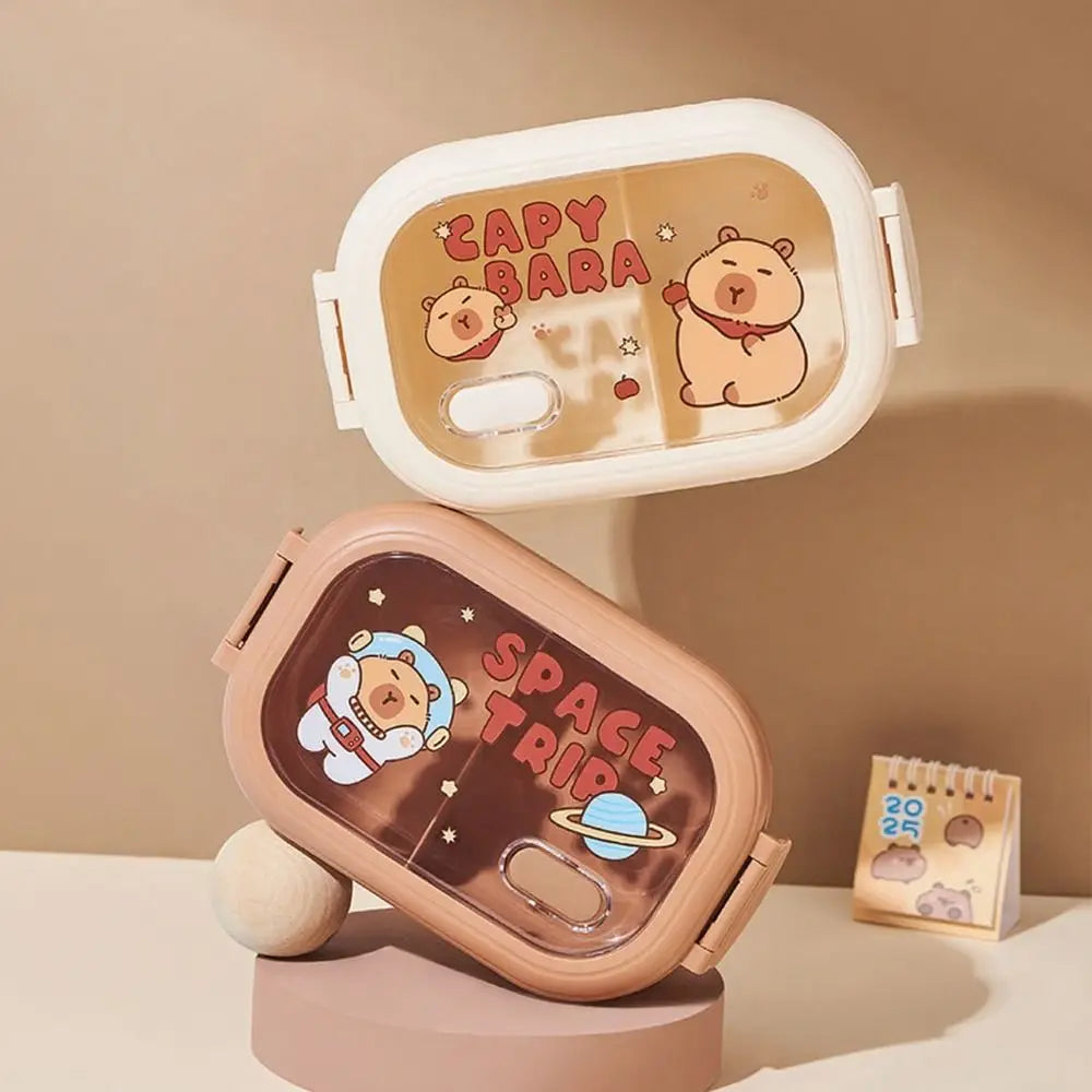 Two kawaii cartoon-themed lunch boxes with 'Capybara' and 'Space Trip' designs on a beige background.