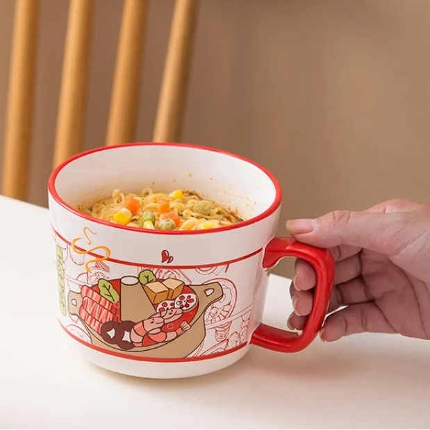 Person holding a large kawaii ramen bowls with food illustration and noodles inside, on a neutral background