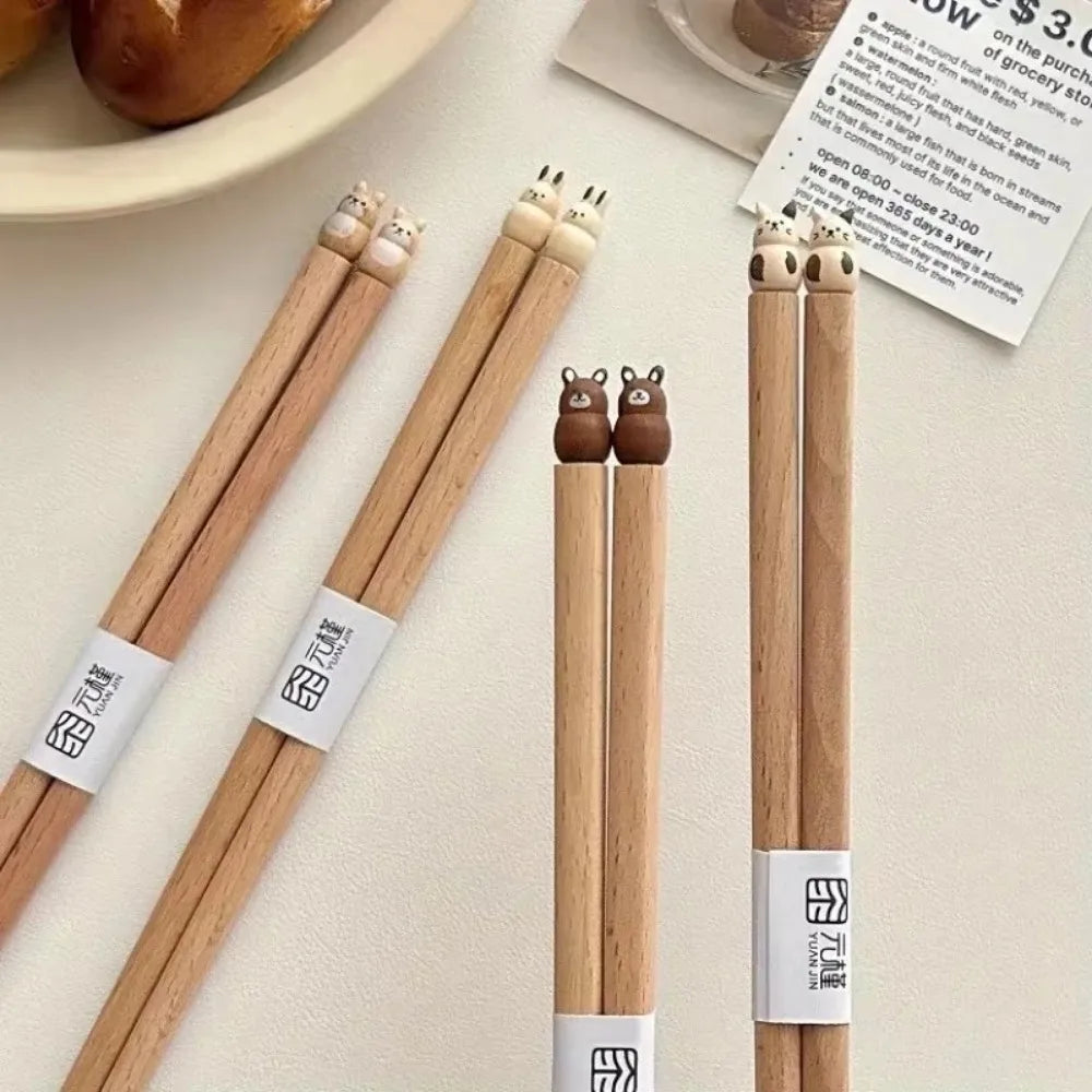Wooden kawaii chopsticks with bear-shaped tips on a light surface