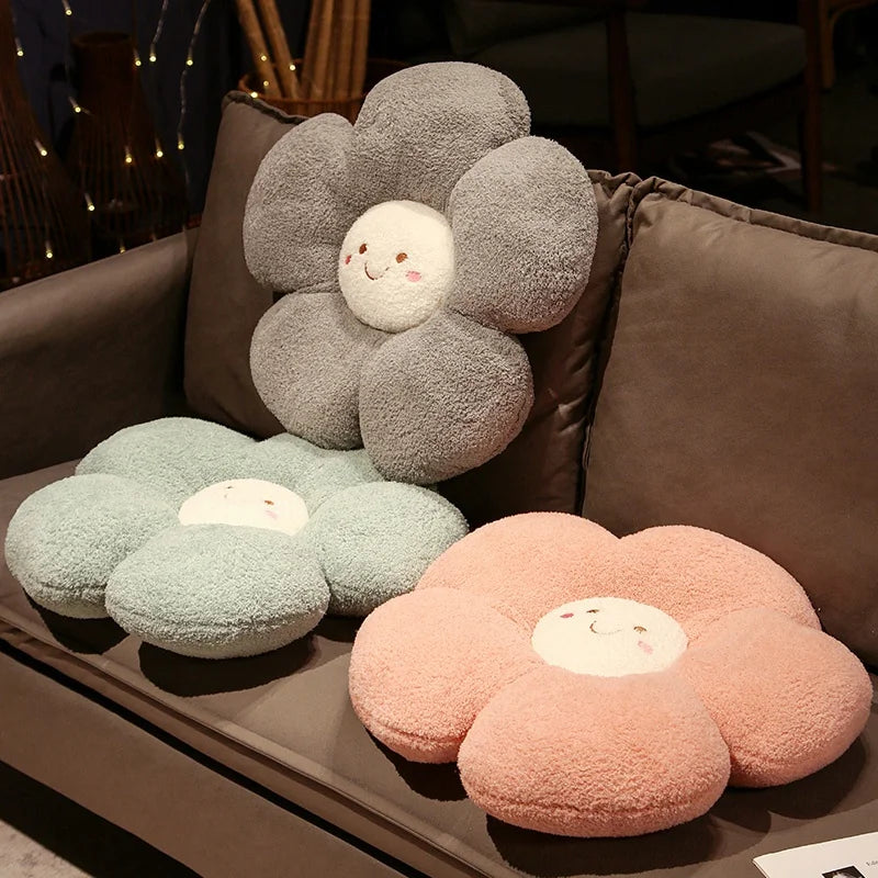 Flower-shaped kawaii cushions in gray, green, and pink on a couch.