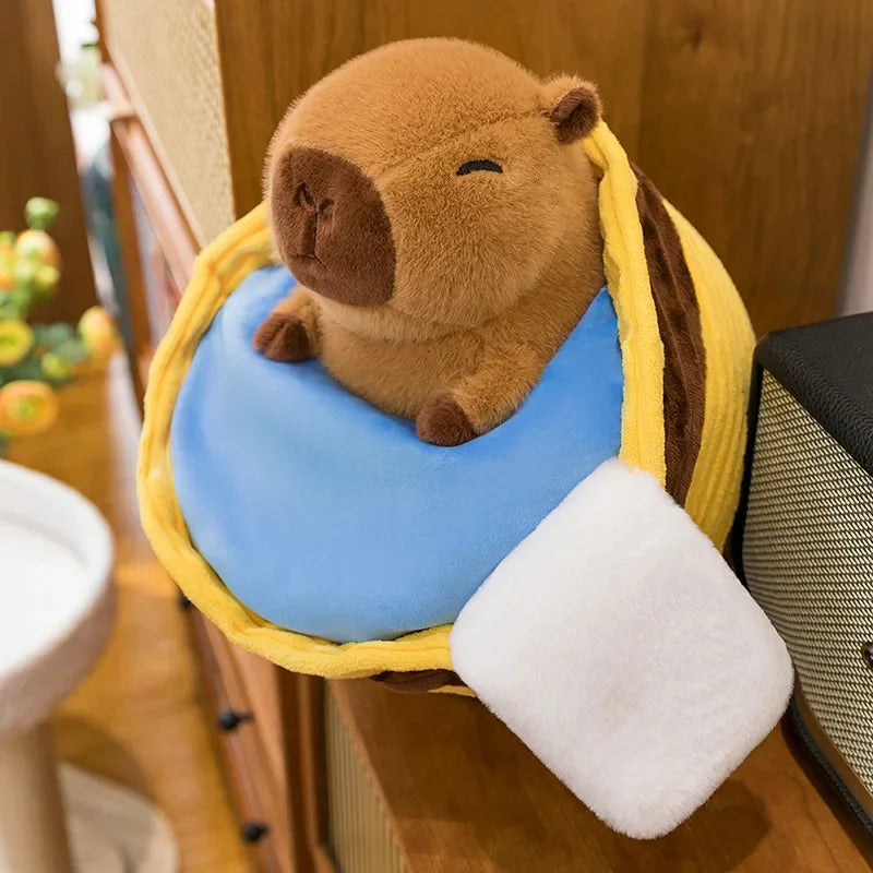 Kawaii plush toy resembling a beaver on a blue cushion with yellow ears, sitting on a wooden surface.