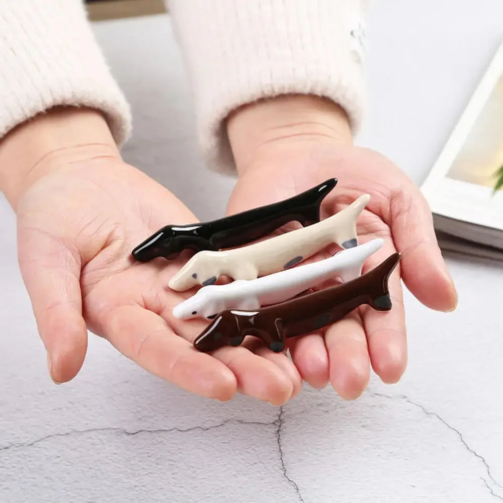 Hands holding four shark-shaped kawaii chopstick holders on a light background