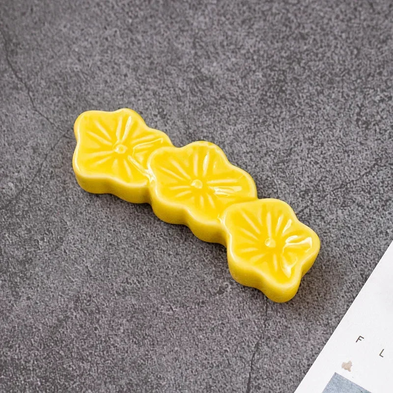 Three yellow flower-shaped kawaii chopstick holder on a gray surface