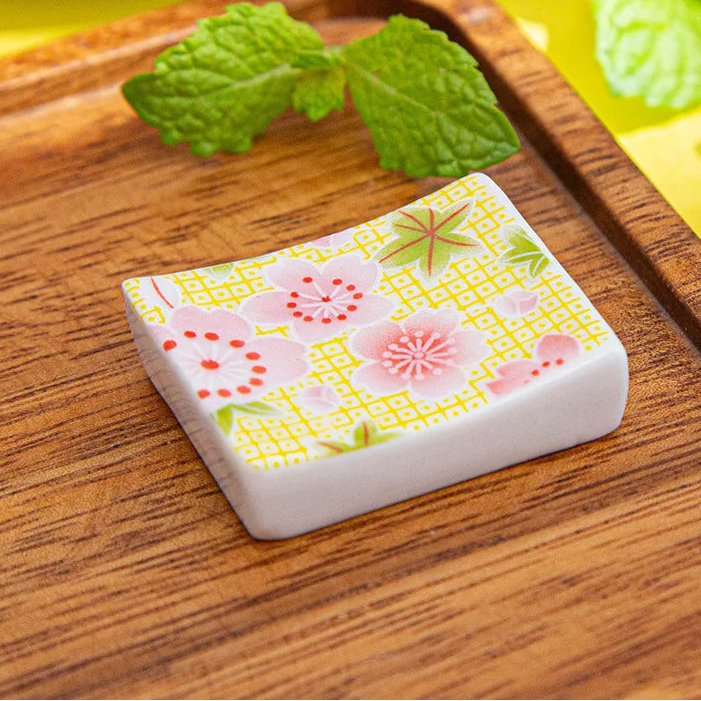 Rectangular ceramic kawaii chopstick holders with floral design on a wooden surface