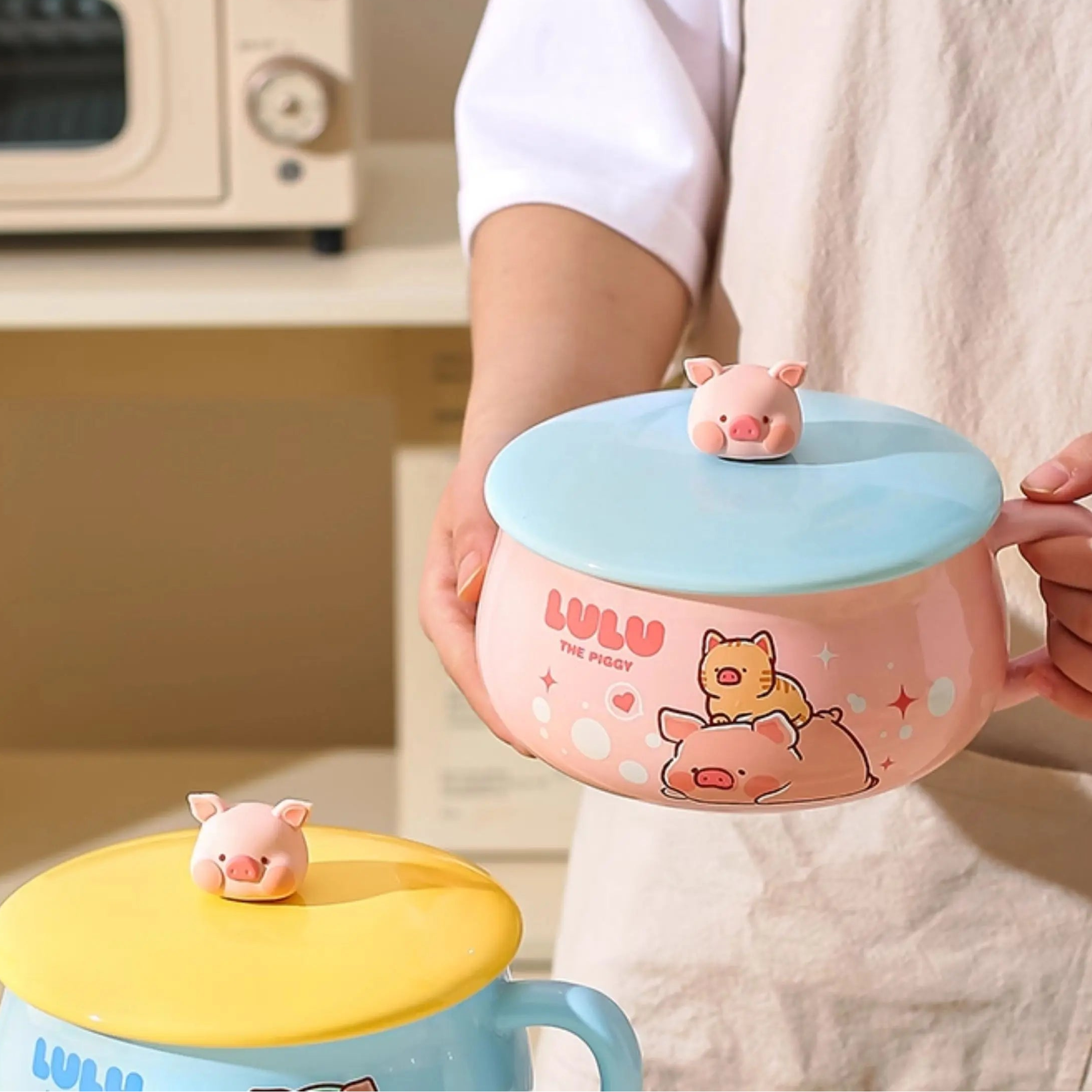 Person holding a cartoon-themed ceramic kawaii ramen bowls with a lid in a kitchen setting