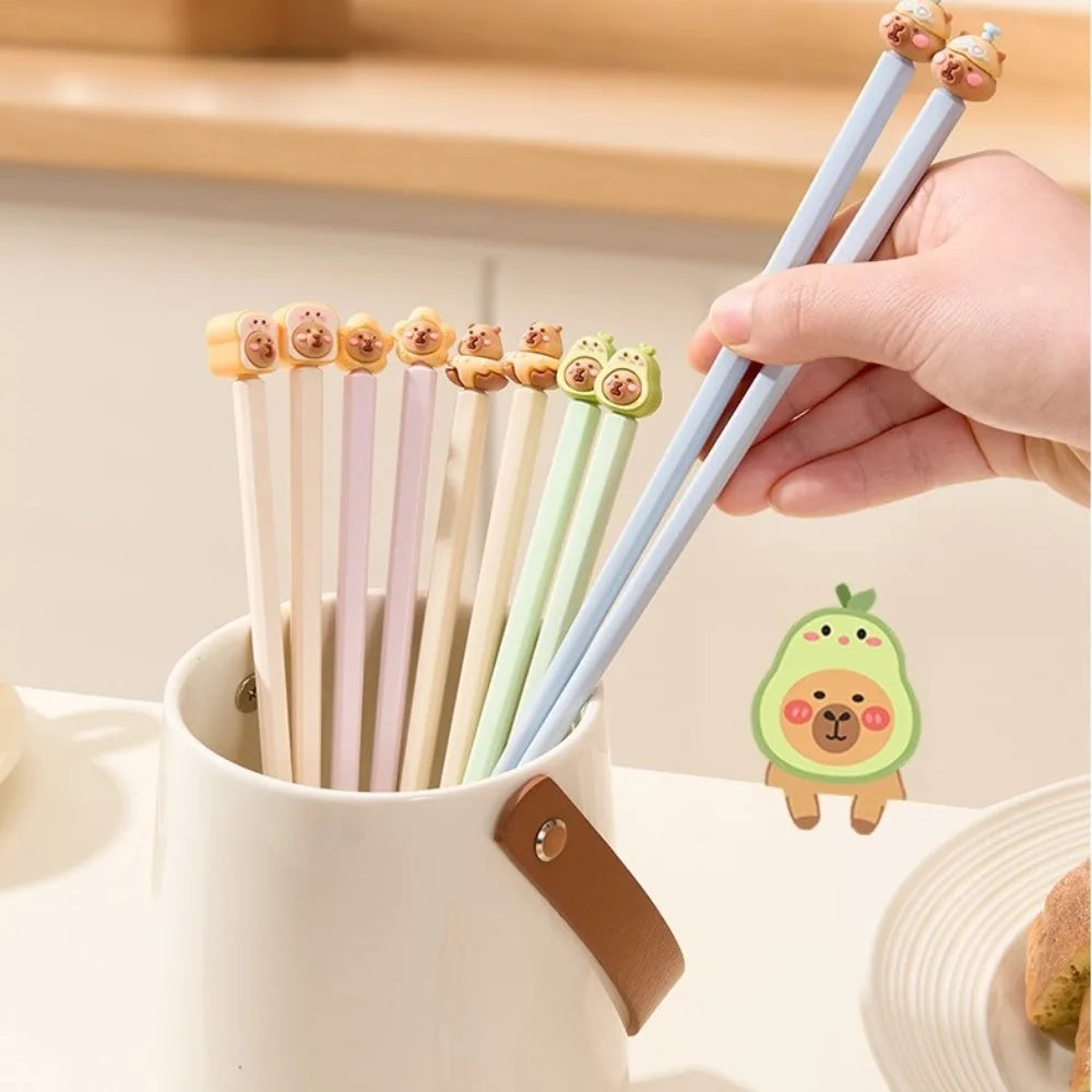 Set of kawaii chopsticks with avocado-themed ends in a holder, held by a hand.