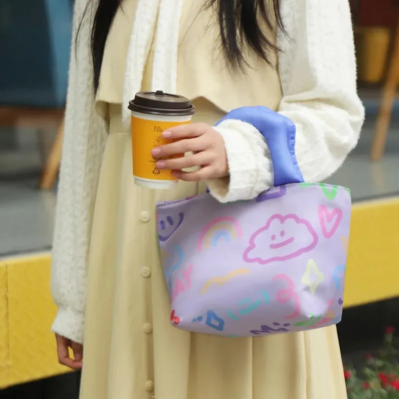 Person holding a colorful kawaii bag with cartoon designs and a coffee cup.