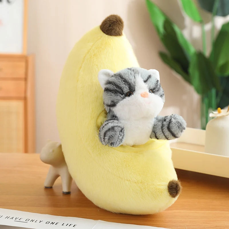 Plush toy cat inside a kawaii plush banana on a wooden surface with a plant in the background