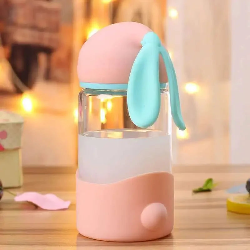 Kawaii water bottle with pink and blue silicone cover on a wooden surface