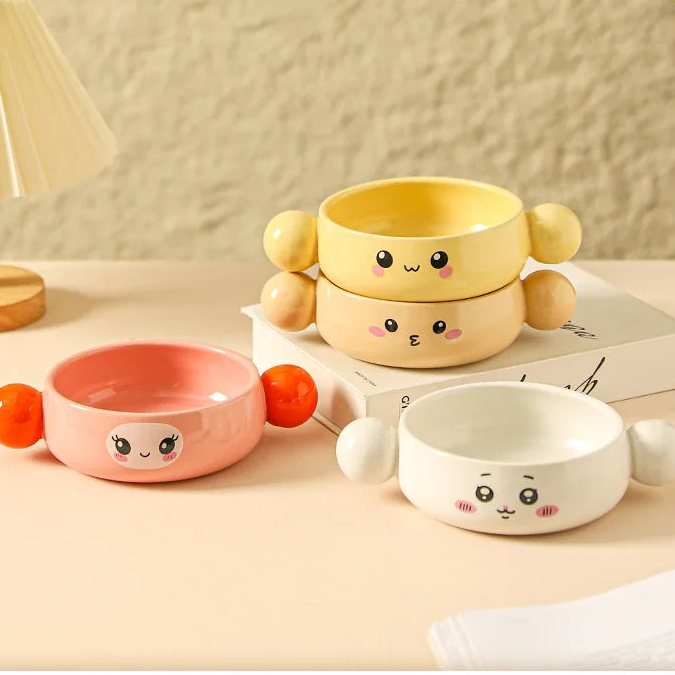 Two cartoon-style ceramic kawaii ramen bowls with faces on a neutral background