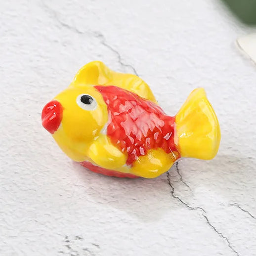Small yellow and red fish-shaped kawaii chopstick holders on a light gray surface with text indicating dimensions.