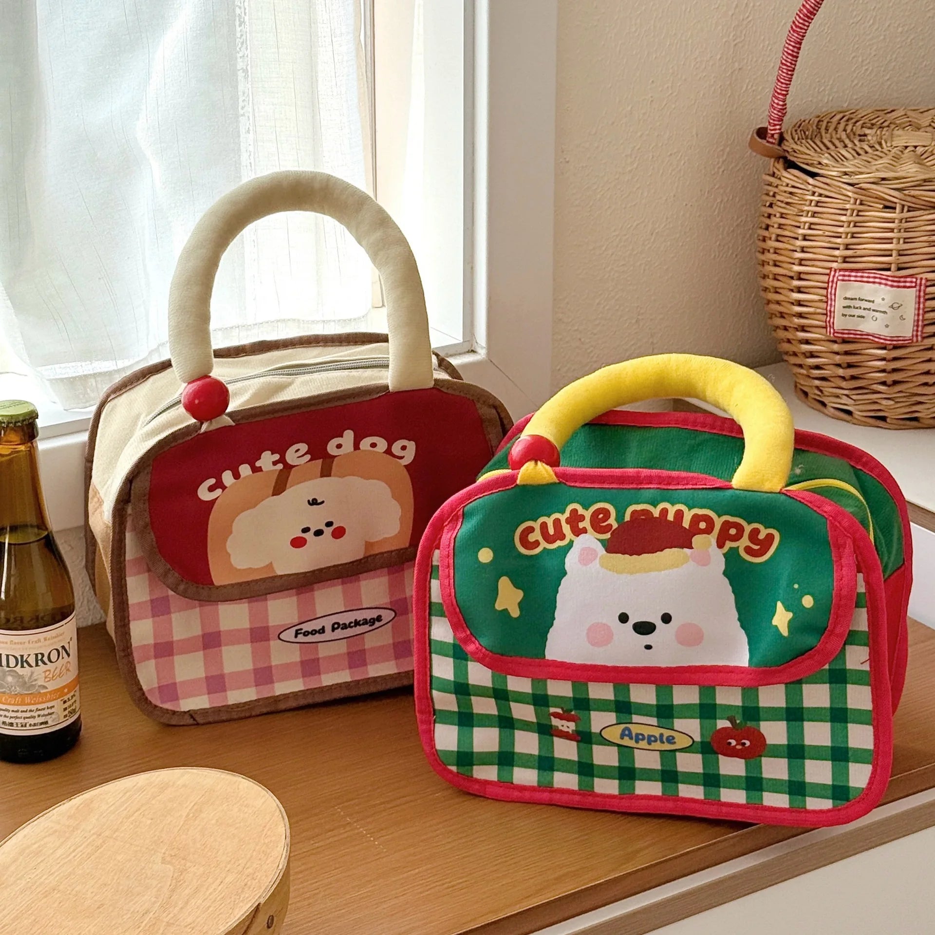 Two cartoon-themed kawaii lunch bags on a wooden surface with a bottle of beer in the background.