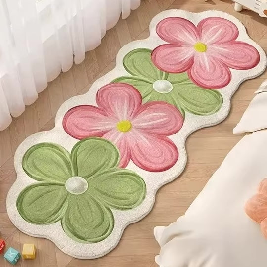 A rug with four flowers in pink and green on a wooden floor.