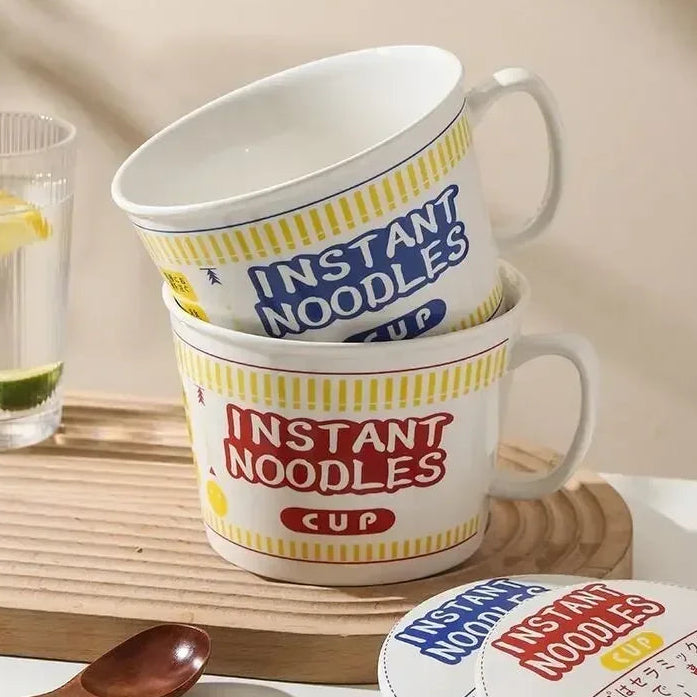 Ceramic kawaii ramen bowl with 'Instant Noodles' design on a wooden tray with a glass of water and lemon.