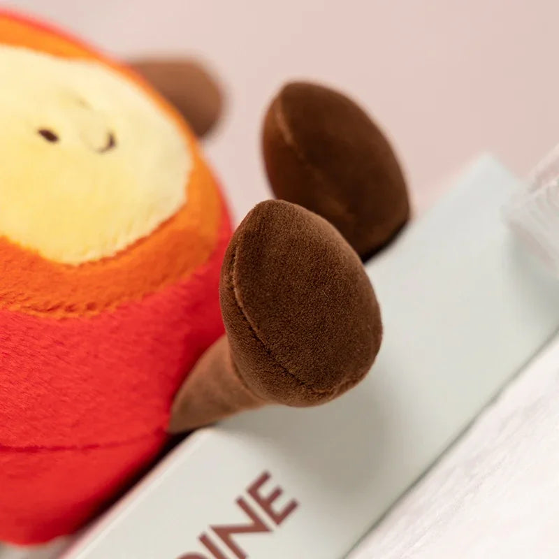 Close-up of a kawaii plush monkey toy with a book on a pink background