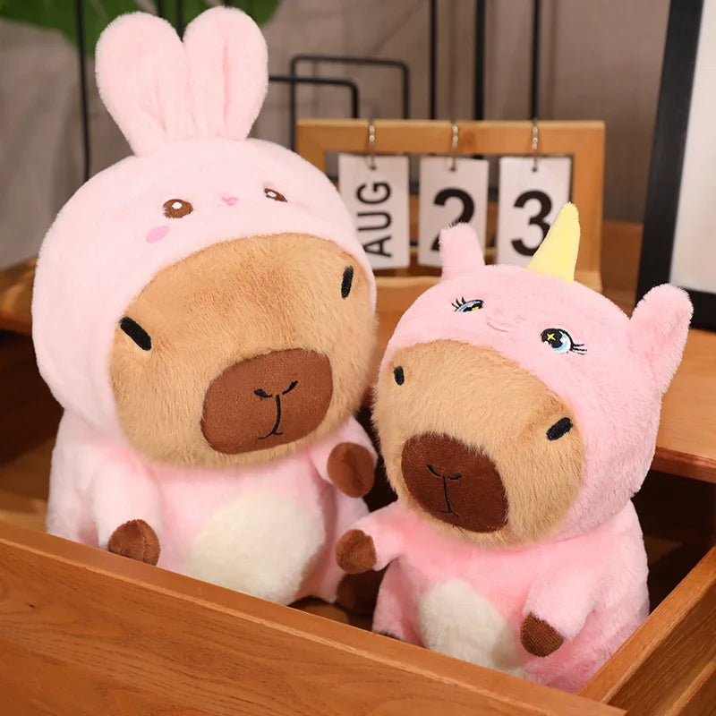 Two kawaii plush toys, one resembling a bear with rabbit ears and the other a unicorn, sitting together on a wooden surface.