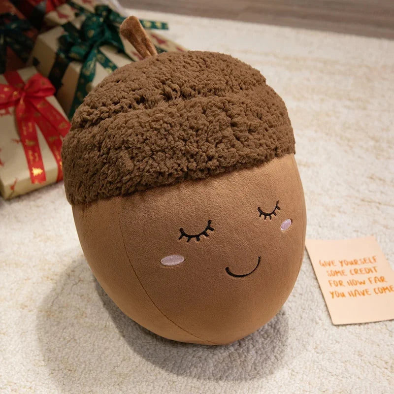 Kawaii plush acorn-shaped toy with a face on a textured surface with gift boxes in the background