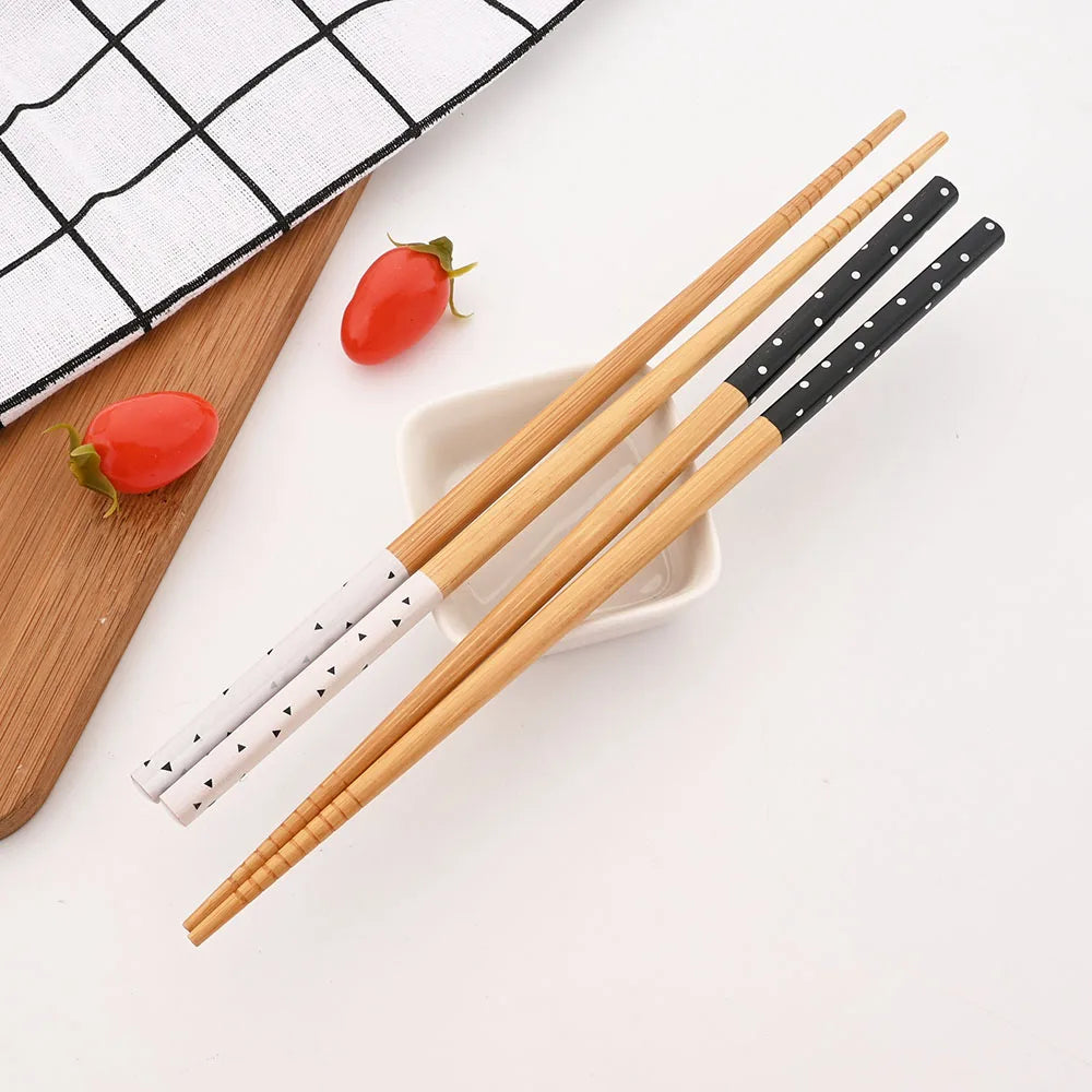 Set of wooden kawaii chopsticks with black and white patterned handles on a white surface.