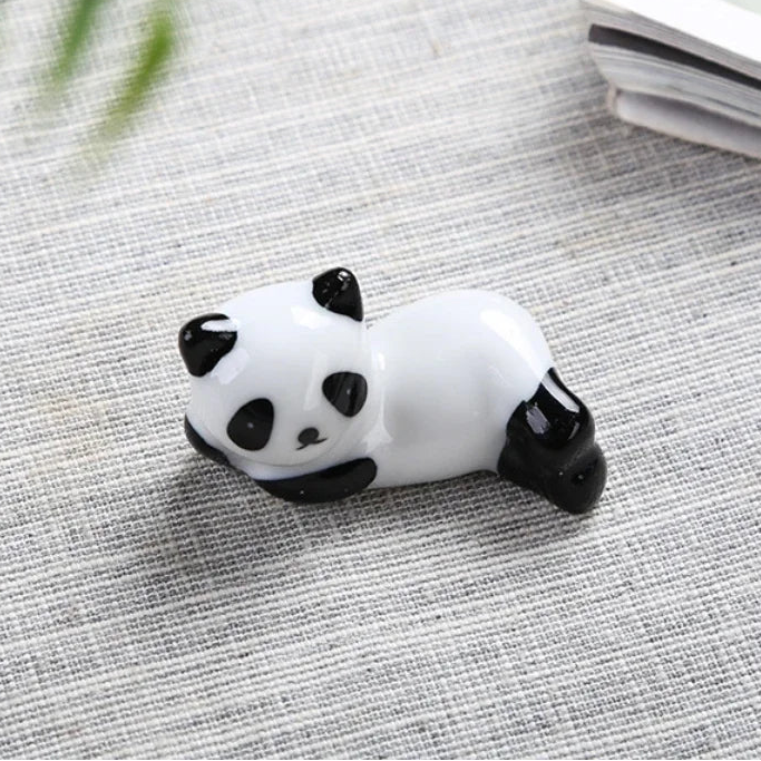 Panda-shaped kawaii chopstick holders on a textured surface