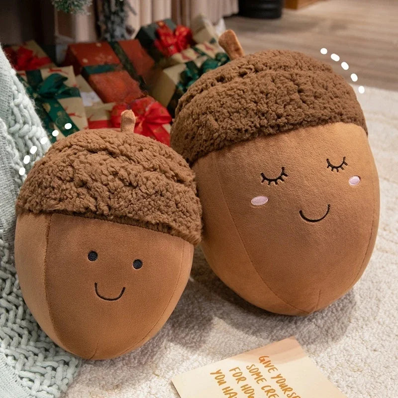 Two kawaii plush acorn toys with faces on a textured surface with gift boxes in the background.