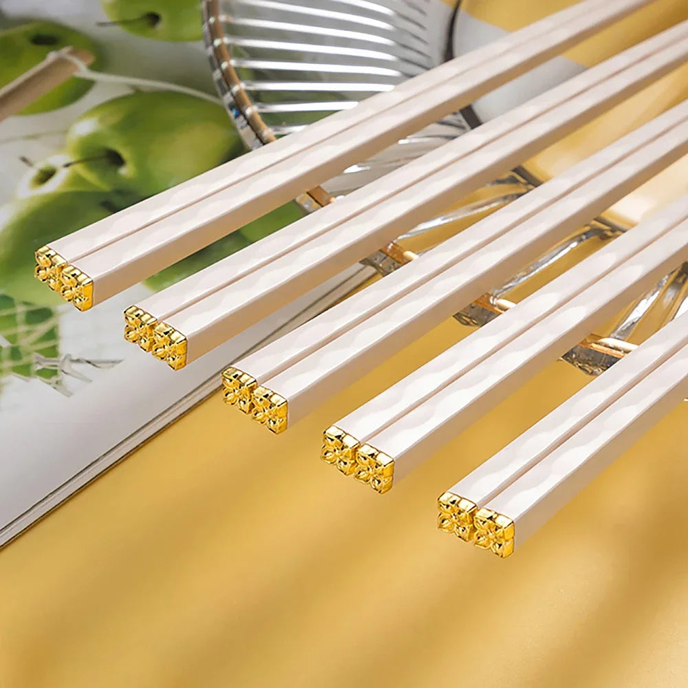 Set of white kawaii chopsticks with gold tips on a yellow background