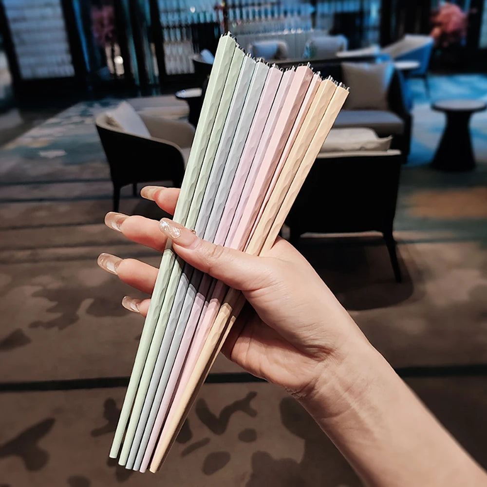 Hand holding a set of colorful kawaii chopsticks in an indoor setting
