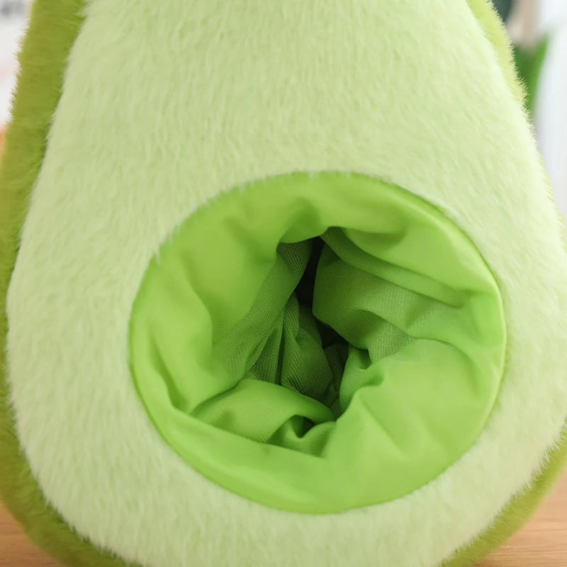 Close-up of a green kawaii plush toy resembling an avocado on a wooden surface.