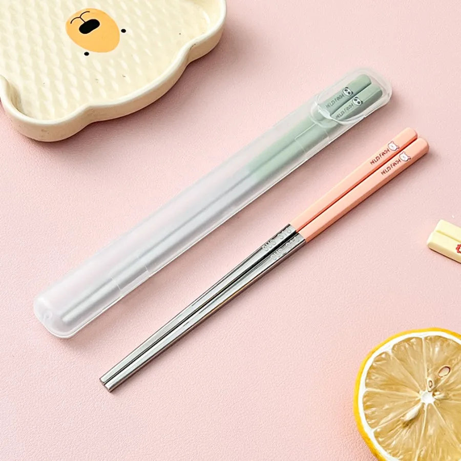 Set of kawaii chopsticks in a clear case on a pink background with a lemon slice and small dish.