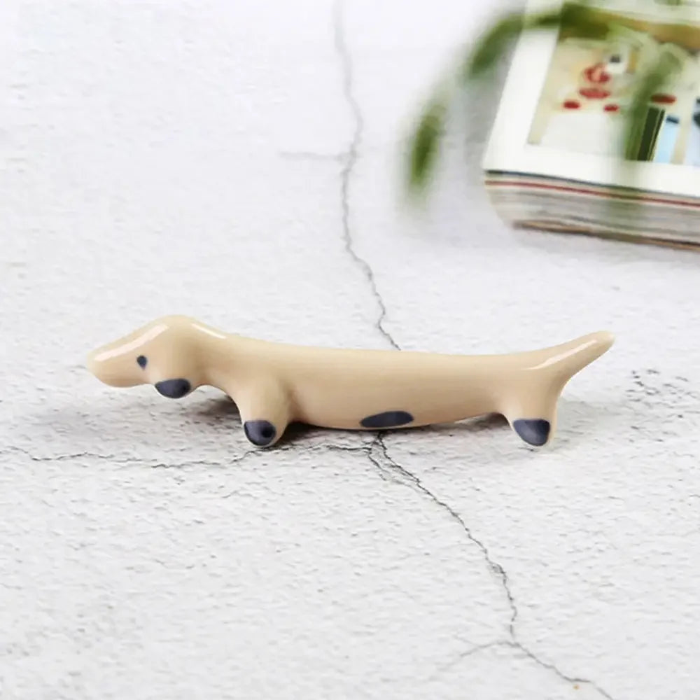 Beige ceramic dog kawaii chopstick holders with black spots on a light gray surface